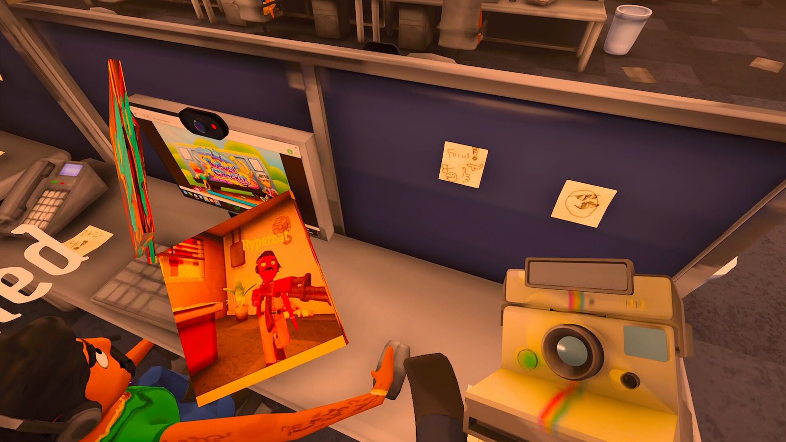 A desk with a polaroid-style camera and a paint app open on the monitor. Official screenshot.